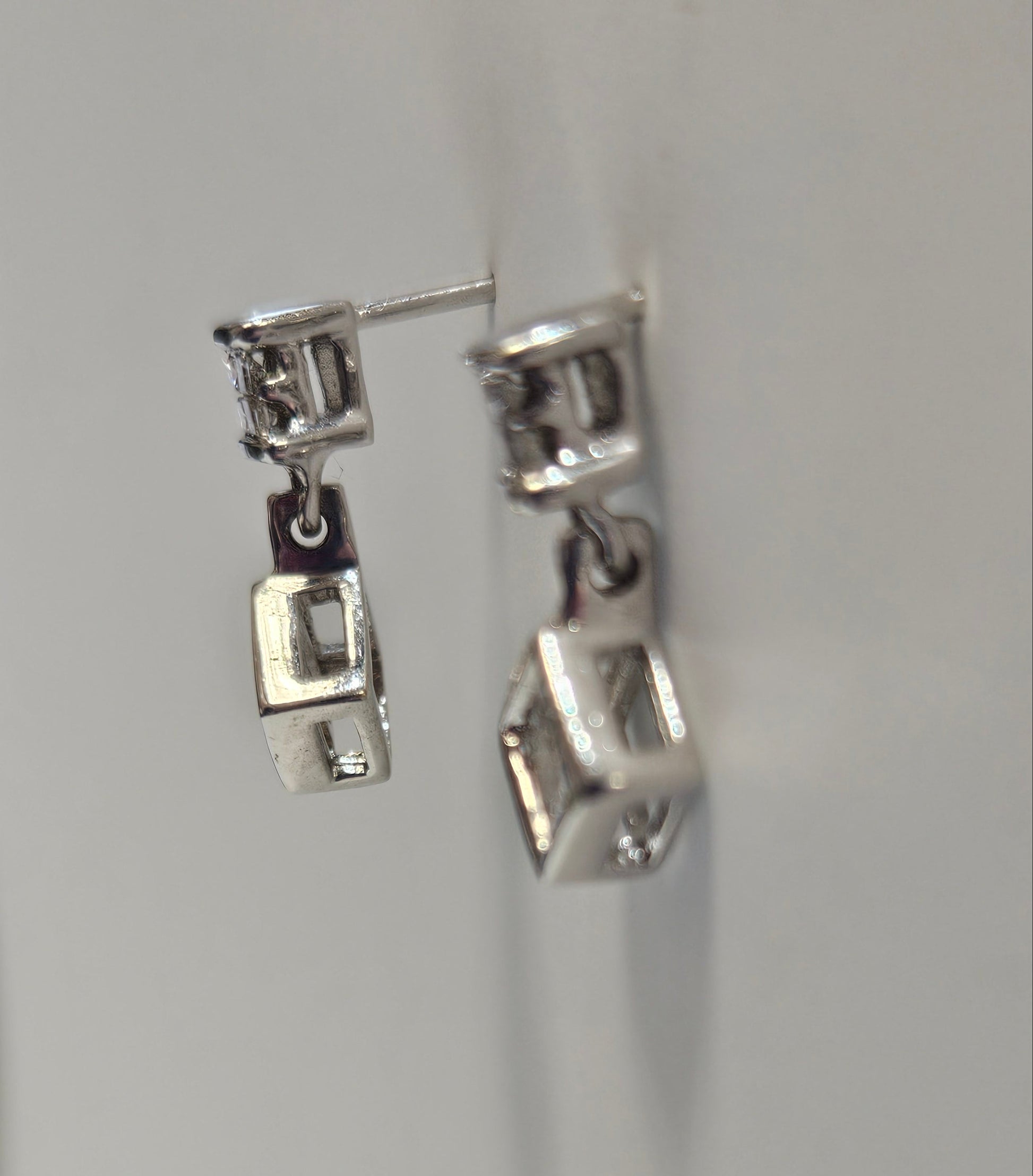 Close-up of a silver earring on a light gray background