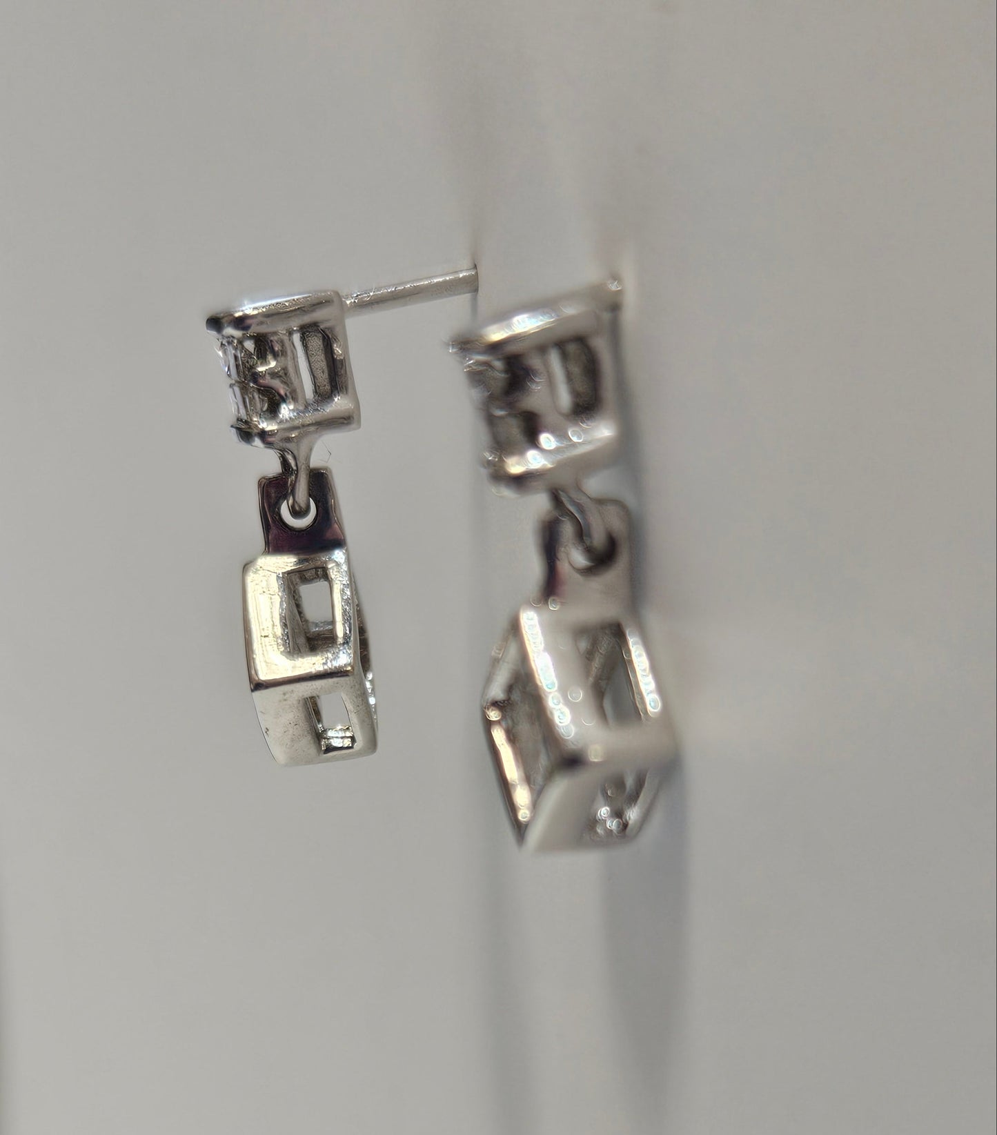 Close-up of a silver earring on a light gray background