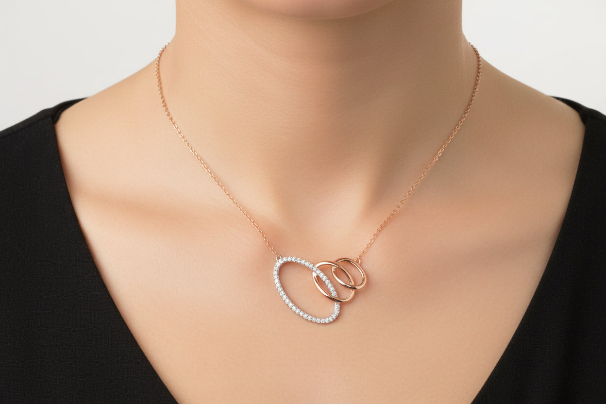Rose gold necklace with interlocking rings and diamonds on a white background